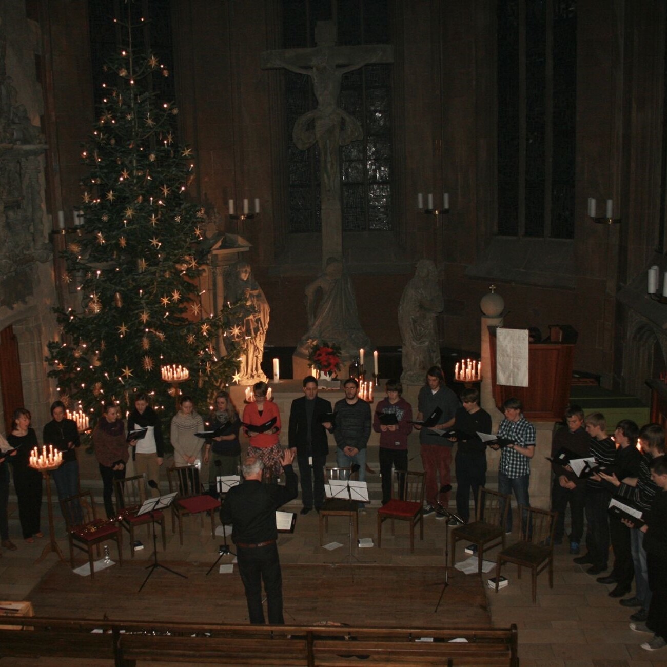 Christmette 2017: Chor singt unter Weihnachtsbaum in Kirche. Festliche Atmosphäre mit Kerzen.