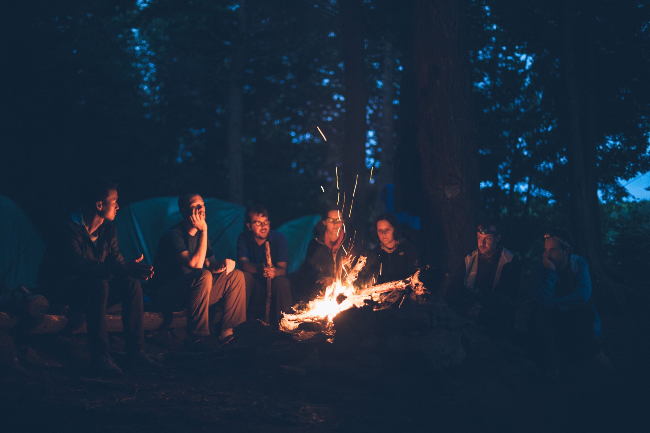 Lagerfeuer mit Freunden: Gemütlicher Abend am Lagerfeuer im Wald. Camping, Natur und Gemeinschaft.