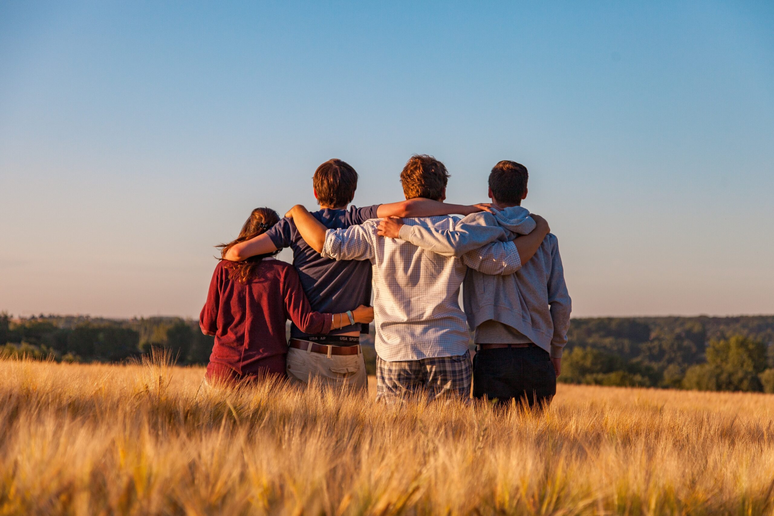 Junge Leute stehen zusammen in einem Feld. Freundschaft und Zusammenhalt im Fokus.